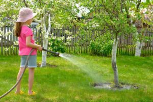 Young girl watering the trees in a garden